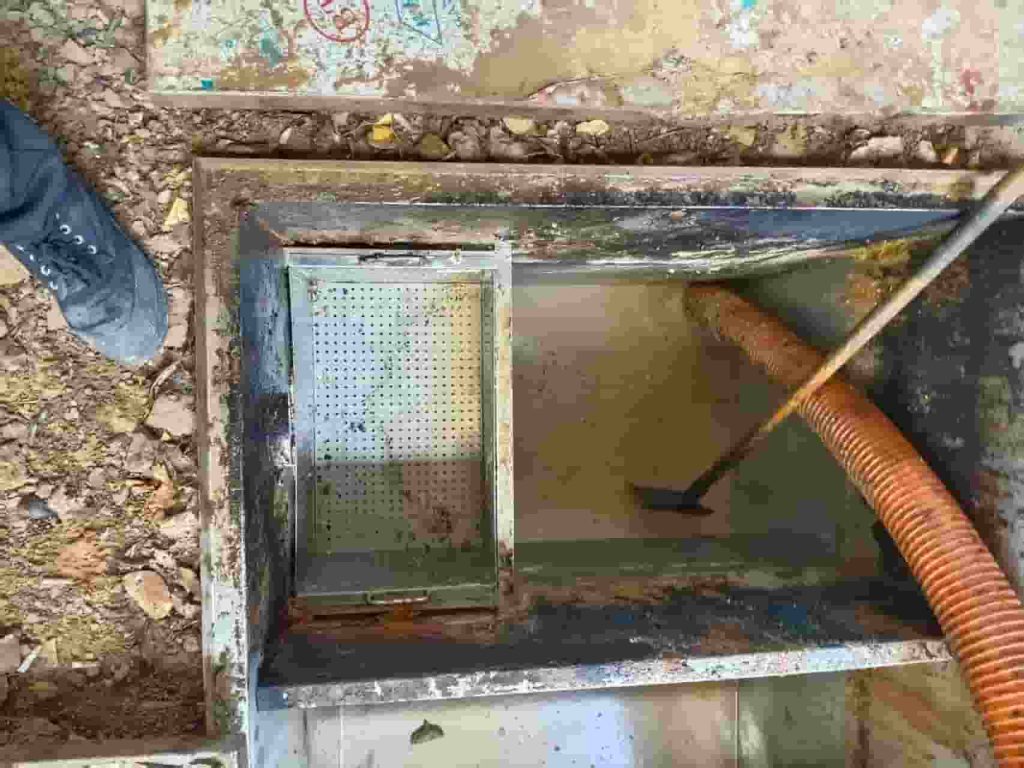 专业人员对餐饮隔油池进行清掏和维护作业